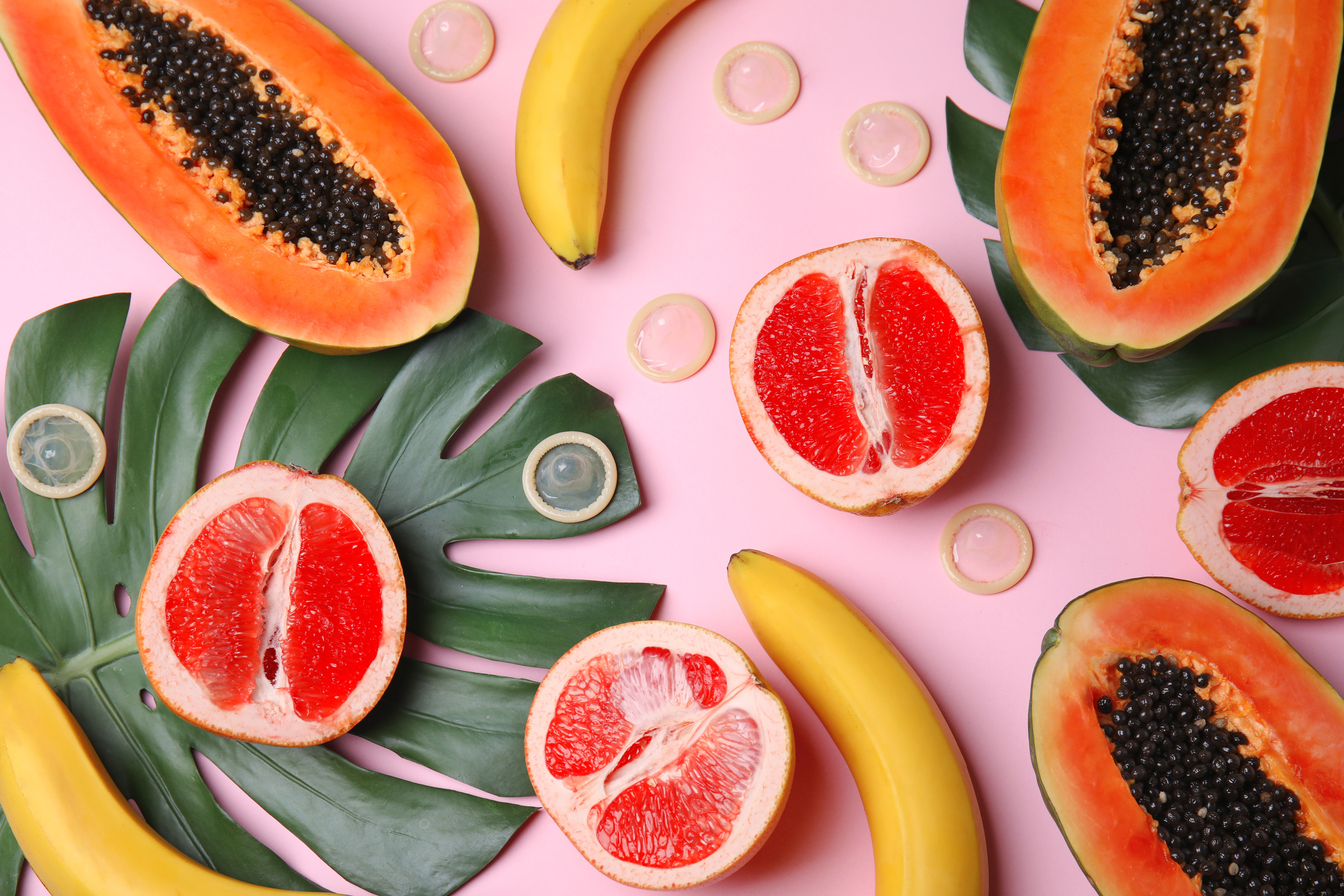Flat Lay Composition with Condoms and Exotic Fruits on Pink Background.  Concept